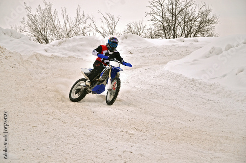 Winter motocross racer on a motorcycle turns with the slope and