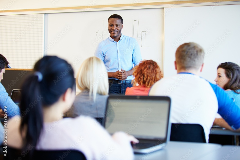Male Tutor Teaching University Students In Classroom Male Tutor Teaching University Students In Classroom