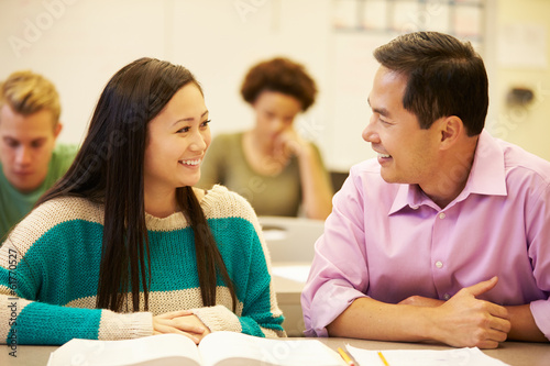 Female High School Student With Teacher Studying At Desk