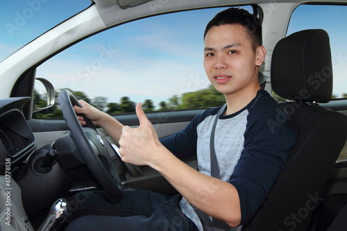 A young man showing thumbs up while driving