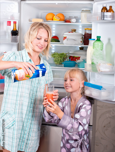 Young mother with a child takes food out of the fridge. photo