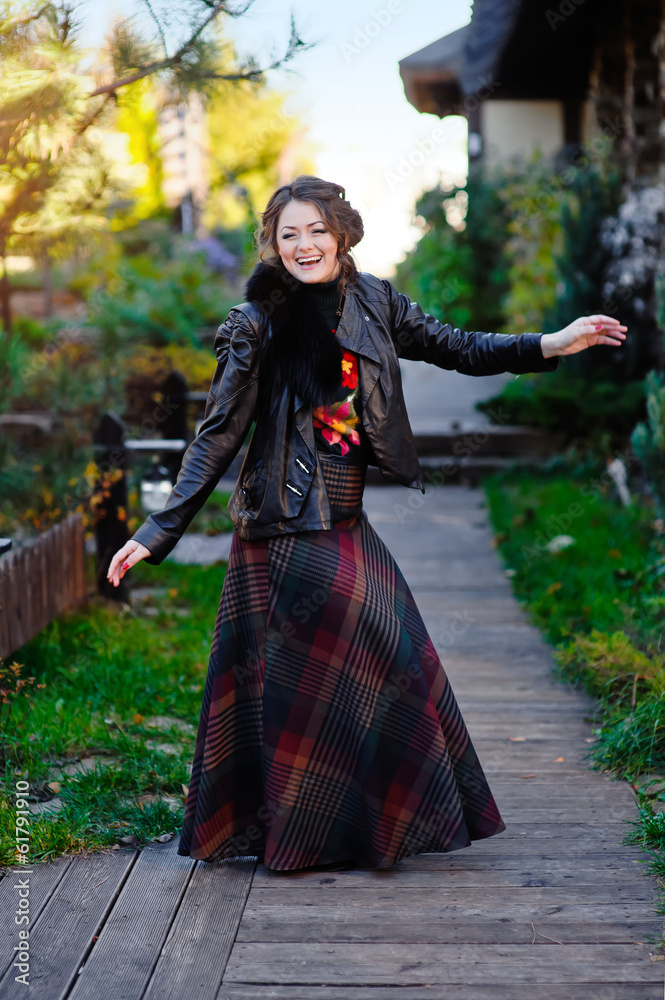 Beautiful girl in a black jacket near wooden house