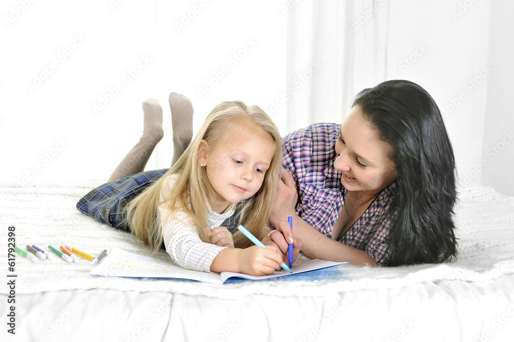 young Mother and little daughter lying and drawing together young Mother and little daughter lying and drawing together