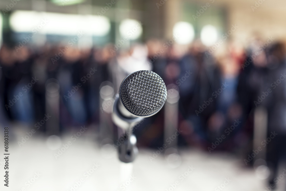 Microphone in focus against blurred audience Microphone in focus against blurred audience
