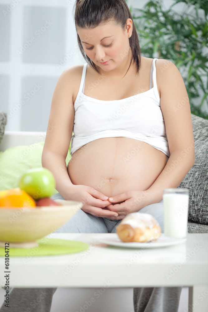 Photo of pretty pregnant woman keeping her hands on belly while Photo of pretty pregnant woman keeping her hands on belly while