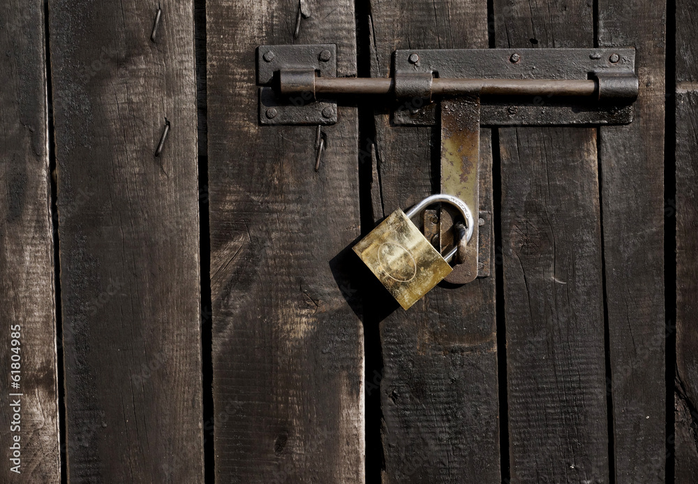 latch with padlock on the door made of wooden black boards latch with padlock on the door made of wooden black boards