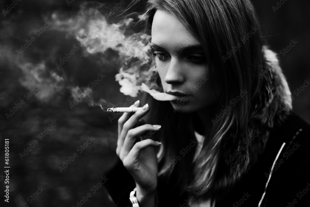 Fototapeta premium Black and white portrait of a beautiful girl smoking