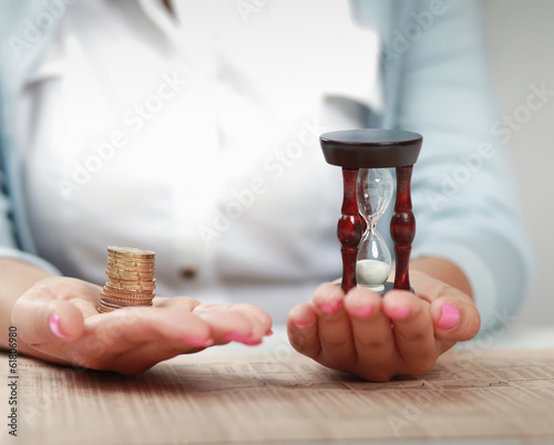 Female hand's with hourglass and coin.