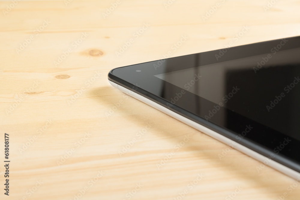 detail of modern black tablet pc isolated on wood table detail of modern black tablet pc isolated on wood table