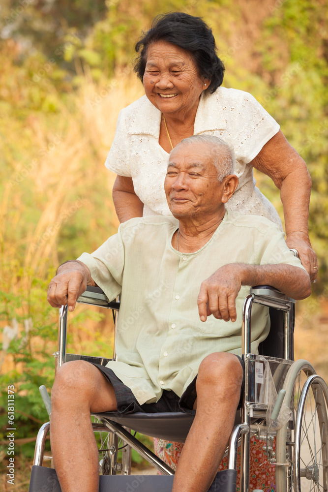 Obraz premium Senior woman pushing her disabled hasband on wheelchair