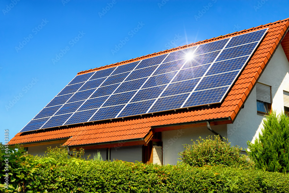 Solardach auf einem Einfamilienhaus reflektiert die Sonne - obrazy, fototapety, plakaty 