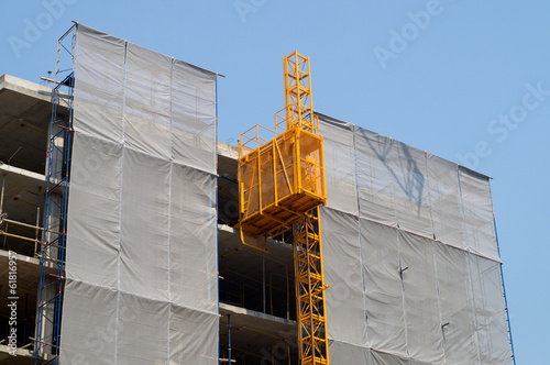 Scaffolding with elevator on facade covered in plastic