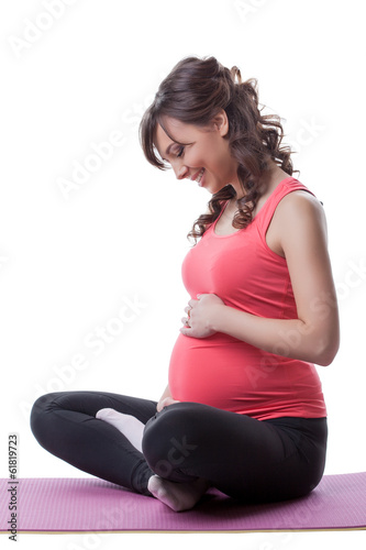 Smiling pregnant woman embraces belly during yoga