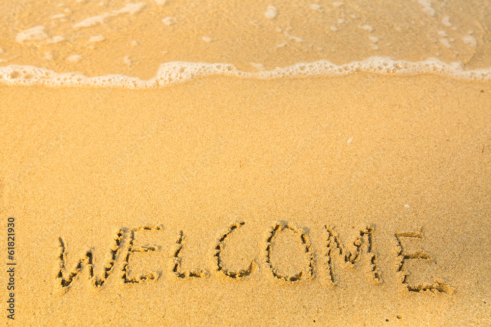 Welcome, written in sand on beach texture, soft wave of the sea.
