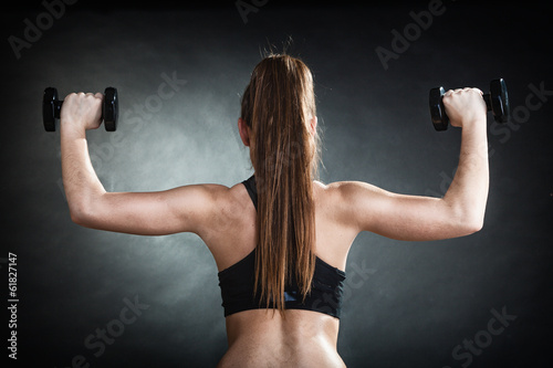 Fitness girl training shoulder muscles lifting dumbbells back