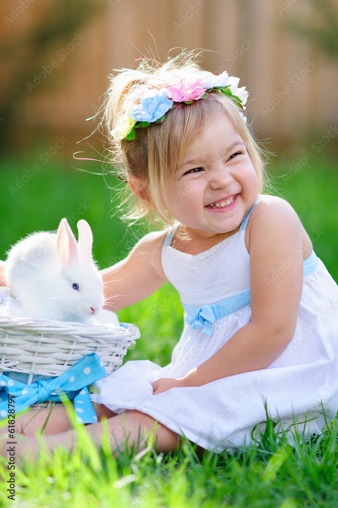 Obraz premium Cute little girl with a bunny rabbit has a easter at green grass