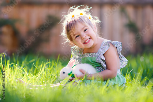 Cute little girl with a bunny rabbit has a easter at green grass