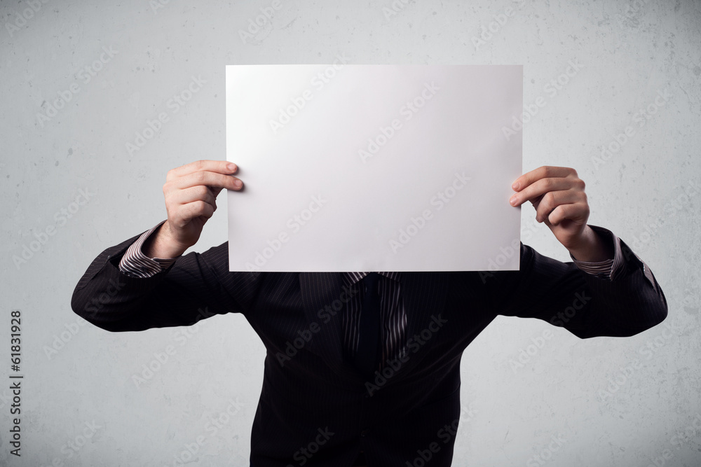 Businessman holding in front of his head a paper with copy space Businessman holding in front of his head a paper with copy space
