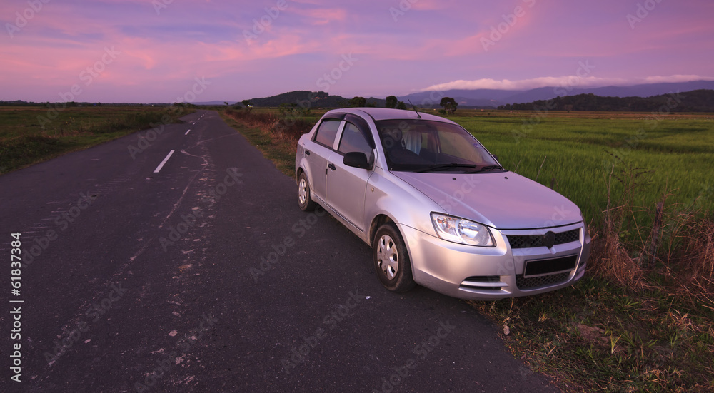 Car parked on roadside in a rural area at sunset