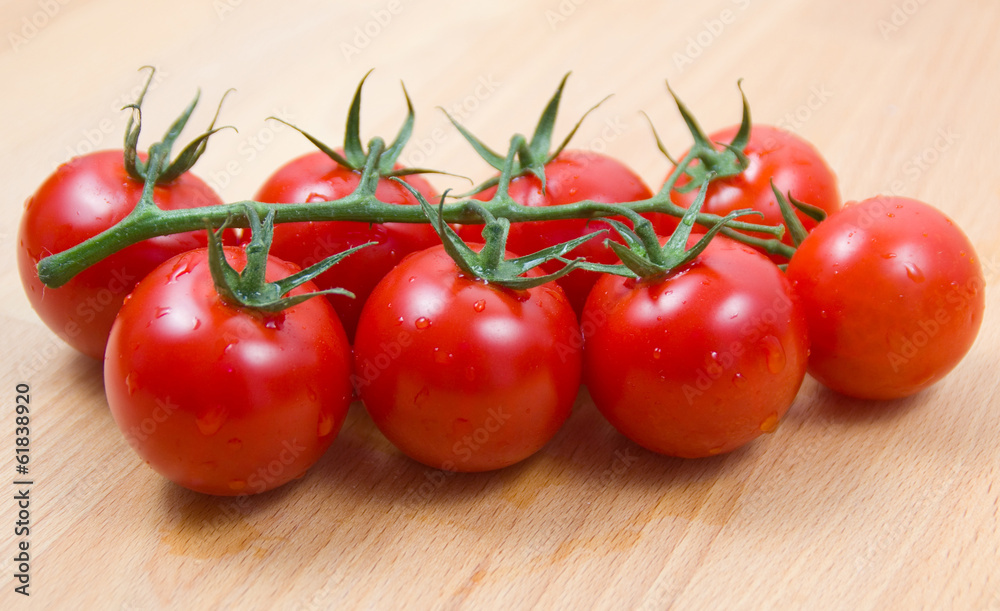 Tomatoes cherry civered by water drops on a wooden board