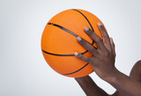 Basketball player holding a ball against gray background