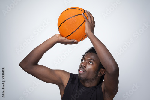 Basketball player throwing the ball against gray background