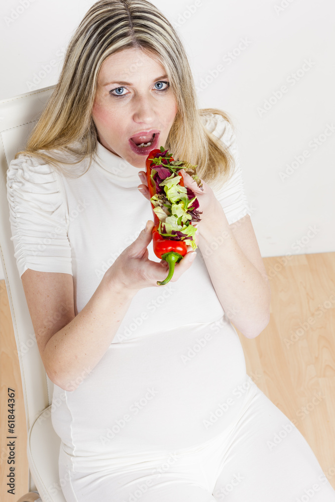 portrait of pregnant woman eating vegetable salad in red pepper portrait of pregnant woman eating vegetable salad in red pepper