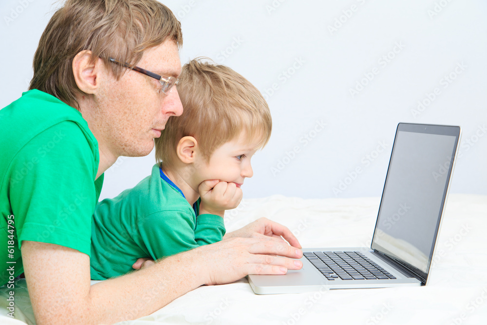 father and son looking at laptop at home