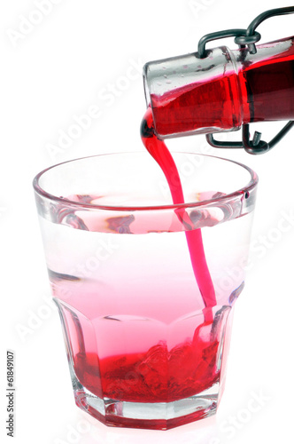 Sirop de grenadine versé dans un verre d'eau photo