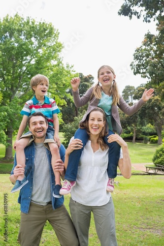 Happy parents carrying kids on shoulders at park