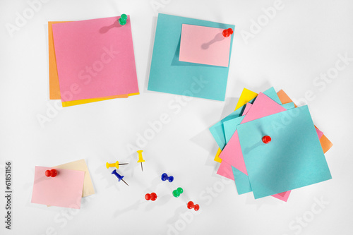 Blank colorful paper notes and colorful pins on white.