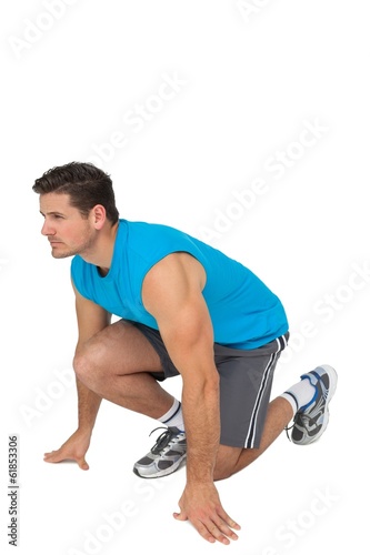 Side view of a young sporty man in running stance