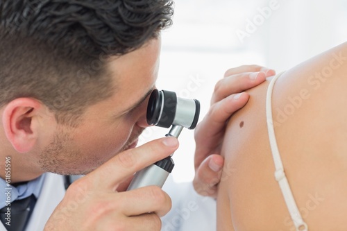 Dermatologist checking mole on woman photo
