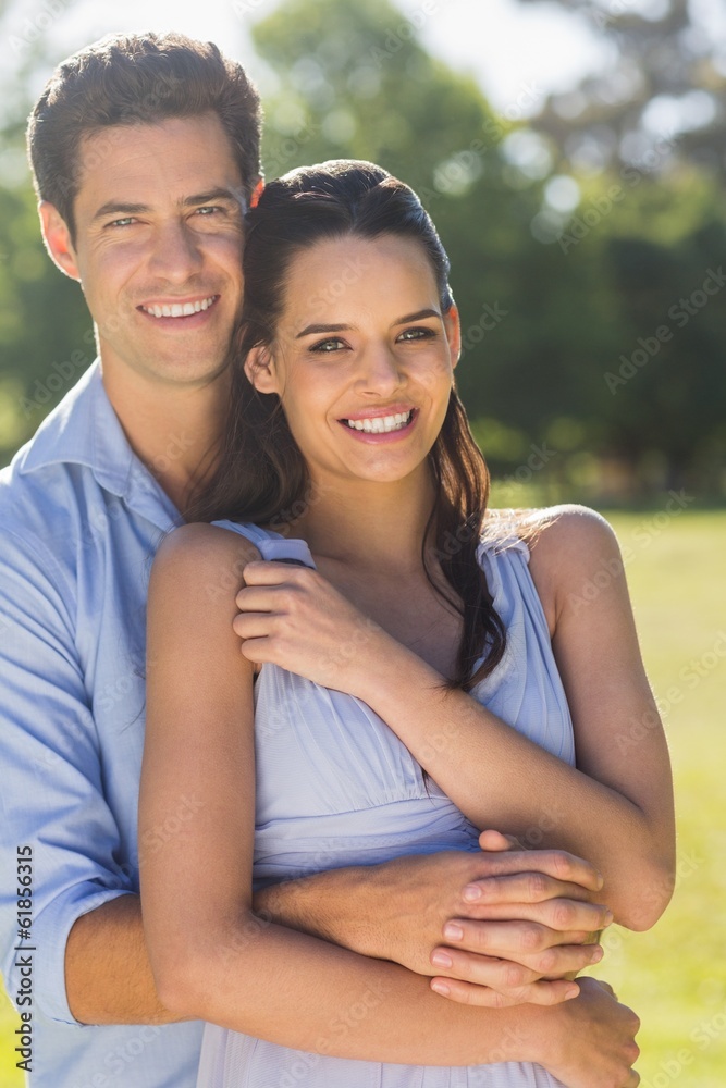 Smiling man embracing woman from behind at park Smiling man embracing woman from behind at park