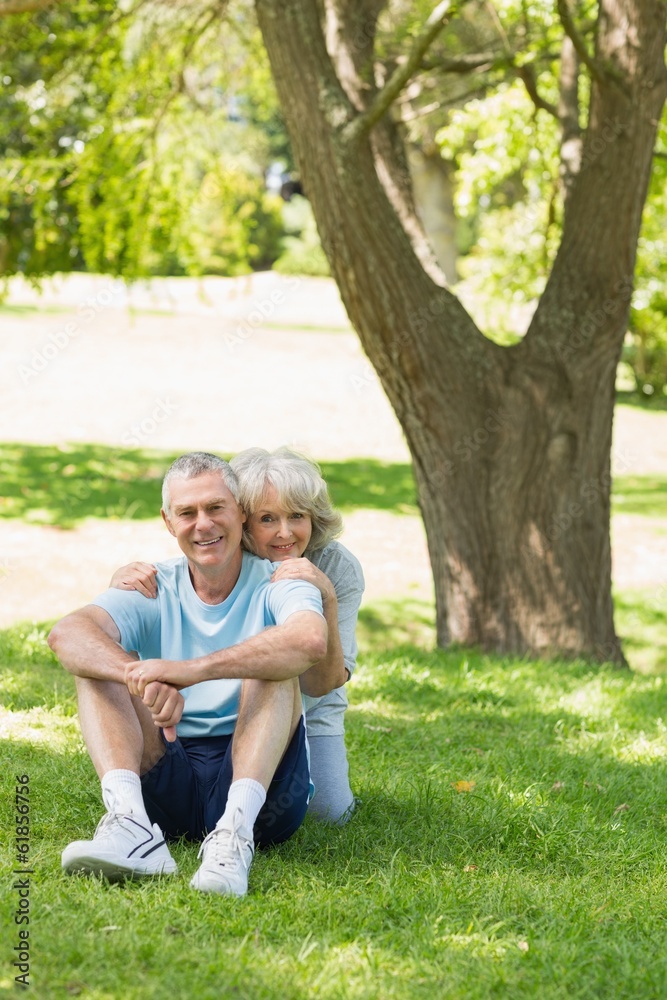 Fototapeta premium Smiling mature couple sitting on grass at park