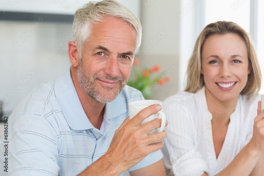 Happy couple having coffee together looking at camera Happy couple having coffee together looking at camera