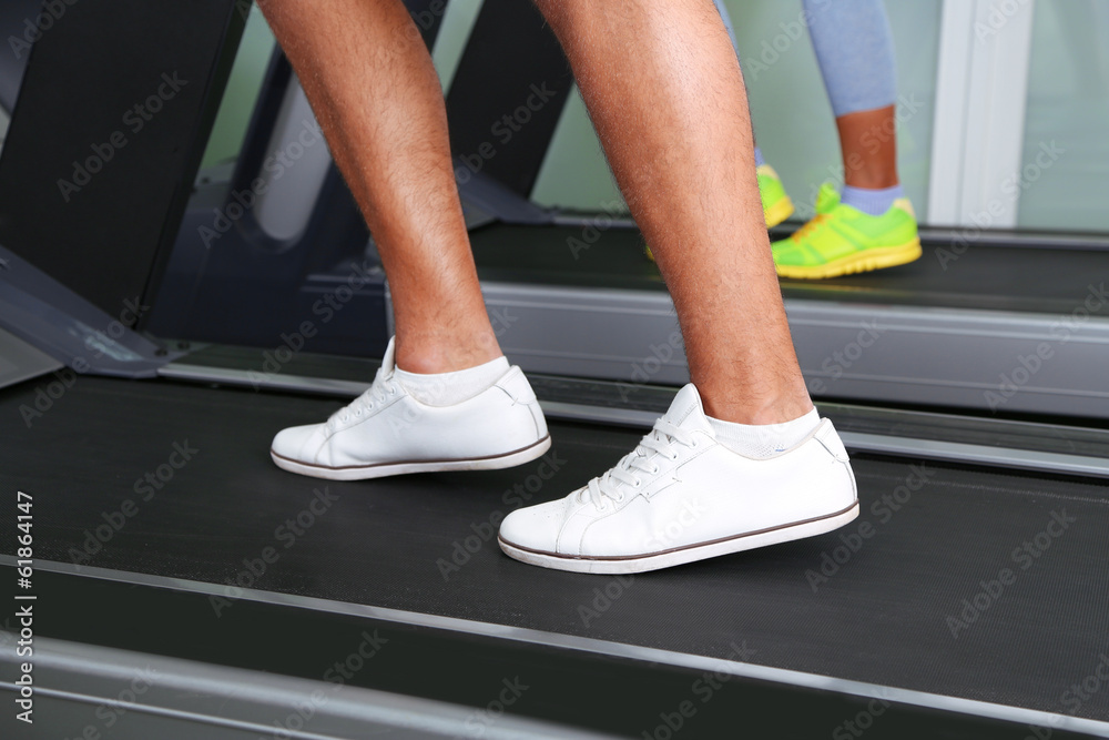 Women and men feet on treadmill close-up Women and men feet on treadmill close-up