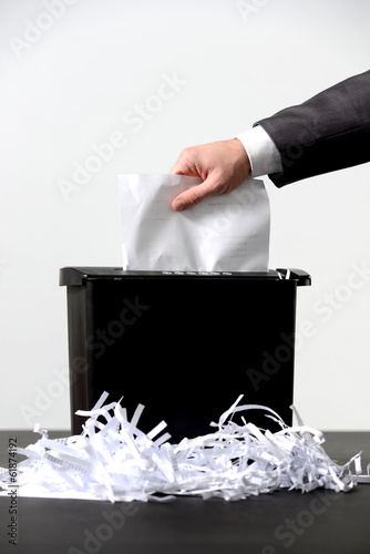 Hand of businessman putting a document in paper shredder