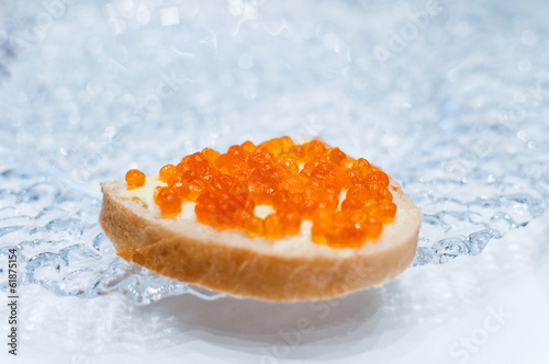 Sandwich with salmon red caviar on a glass plate