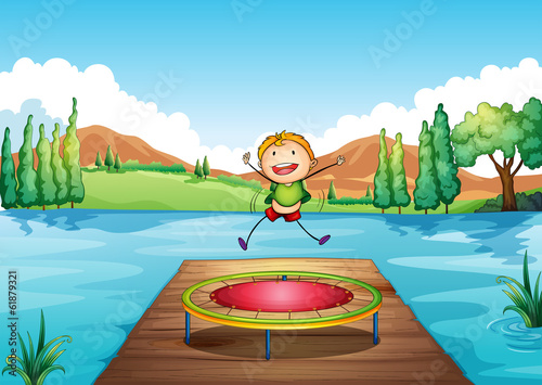 A boy playing with the trampoline at the river
