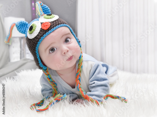 Cute baby lying on the bed with Owl hat