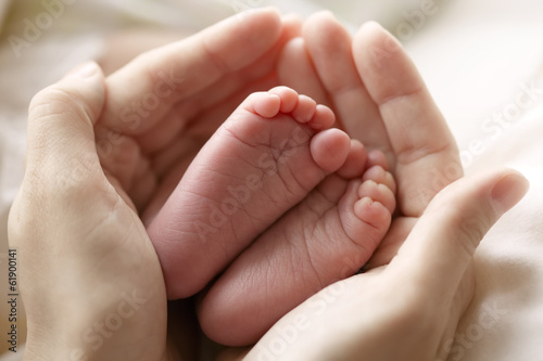 mother hold feets of newborn child