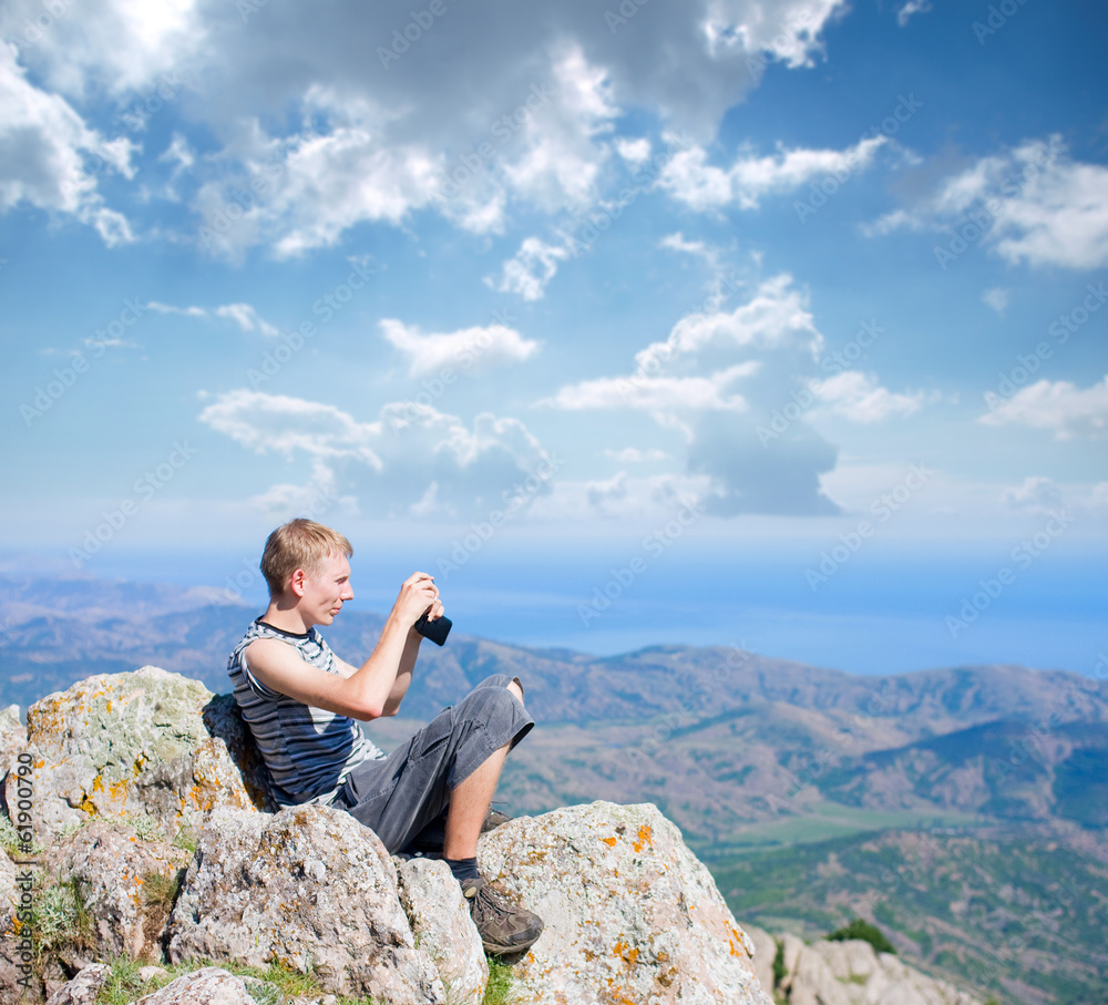 Naklejka premium tourist on top of a mountain takes a snapshot of the nature