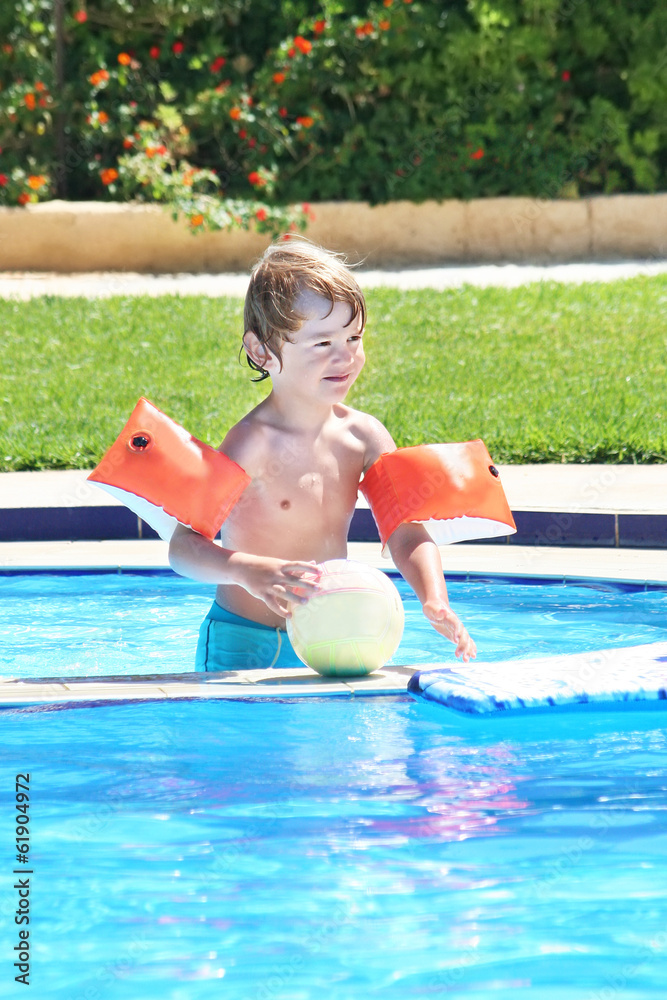 Little boy playing with a ball in a swimming pool
