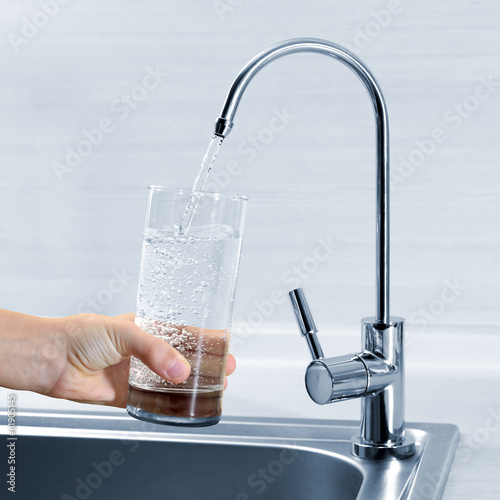 Filling glass of water in hand from kitchen faucet