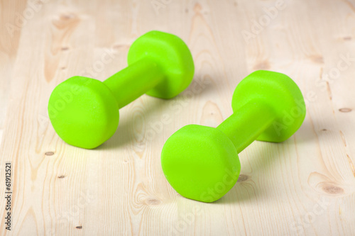 small green dumbbells on wooden surface