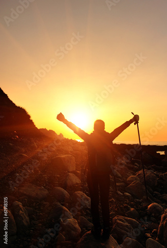 cheering hiking woman open arms at sunrise seaside