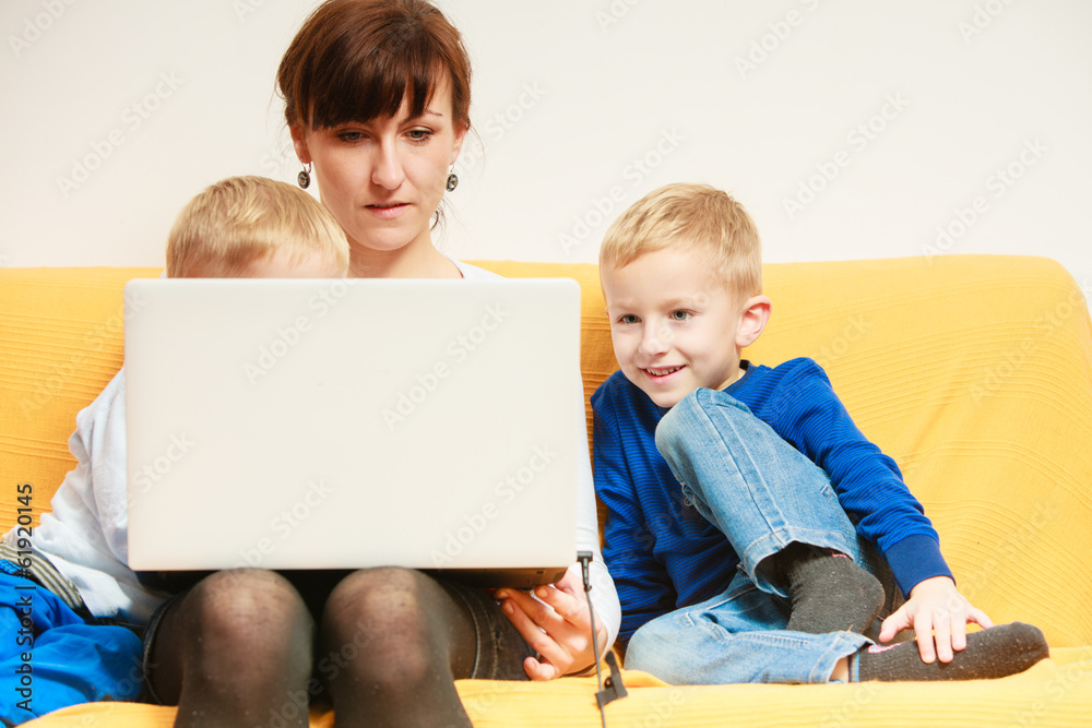 Family. Mother and sons using laptop sitting on sofa at home Family. Mother and sons using laptop sitting on sofa at home
