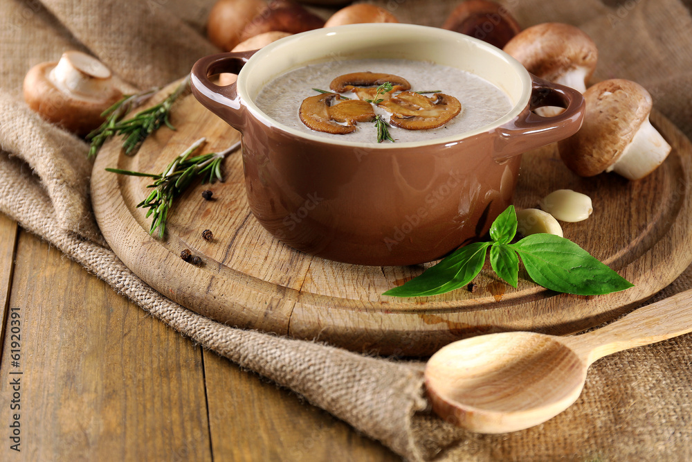 Mushroom soup in pot, on napkin, on wooden background Mushroom soup in pot, on napkin, on wooden background