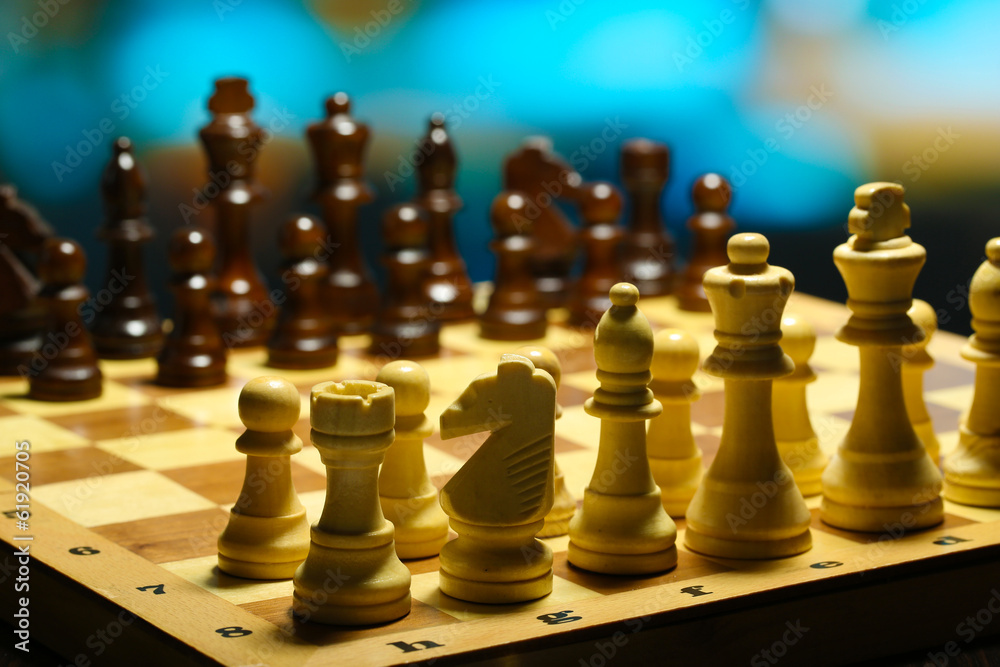 Chess pieces on board on bright background Chess pieces on board on bright background